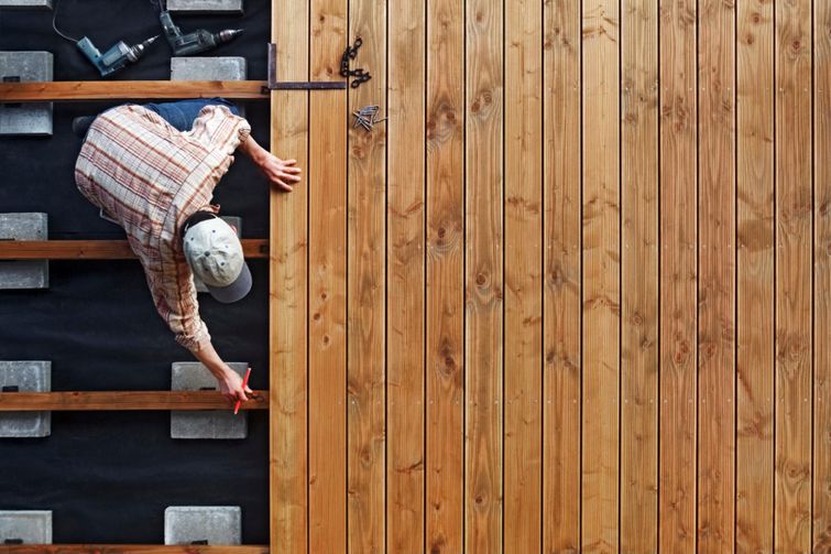 A man scaling a wooden fence during deck building.