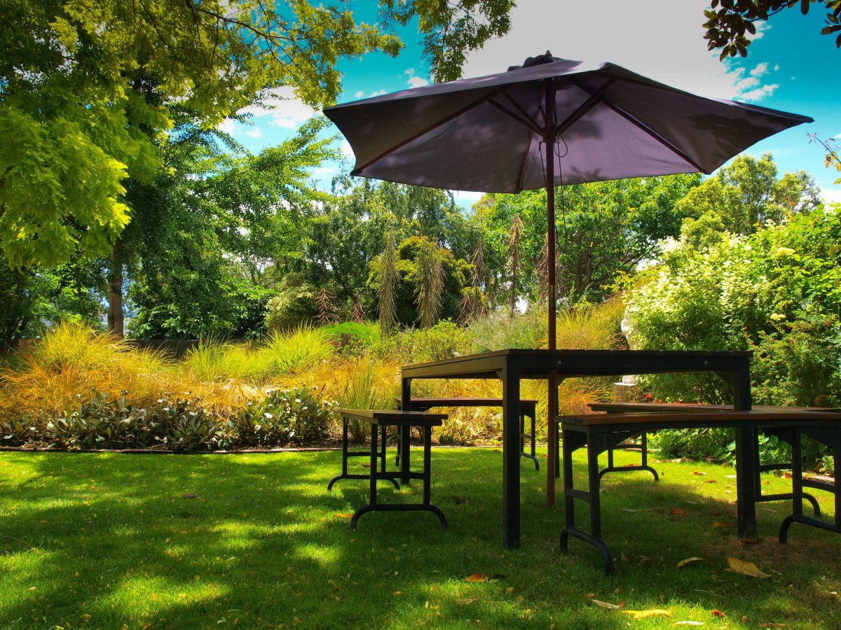 a picnic table with an umbrella in the middle of a grassy area.