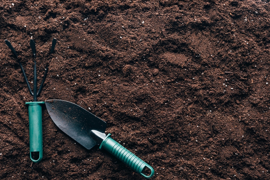 A garden tool resting on a mound of the best soil.