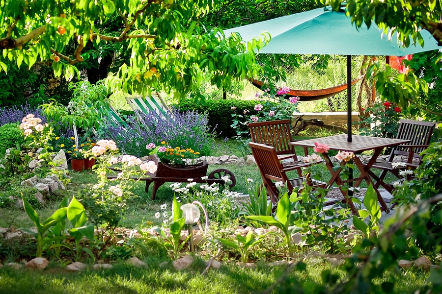 A garden featuring a table, chairs, and umbrella as functional garden ideas.