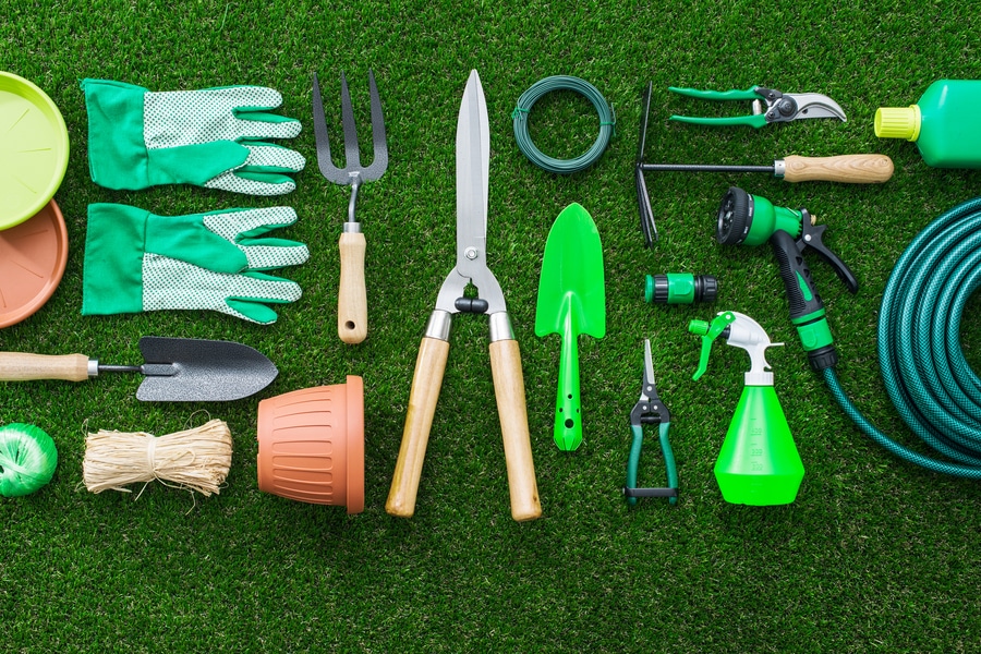 A 2022 selection of gardening tools spread out on the lawn.
