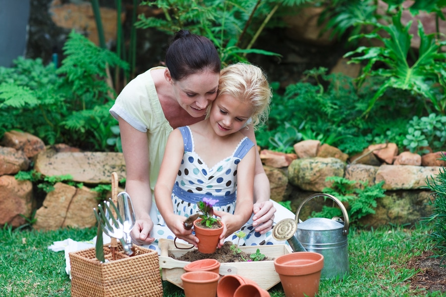 A mother and her daughter enjoy Gardening With Kids in their blooming garden.