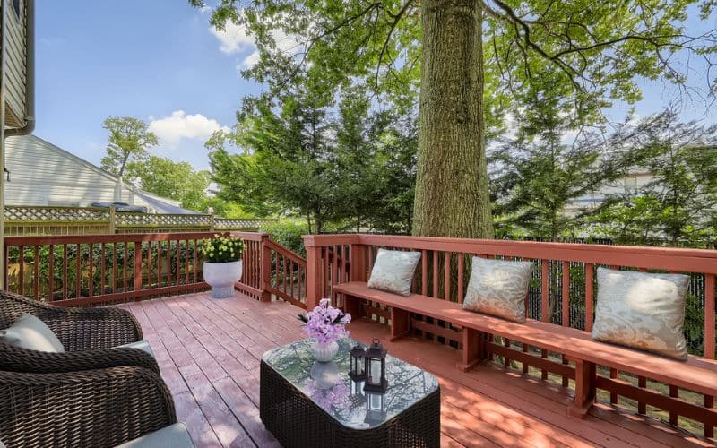 patio and a wooden deck with wicker chairs and a table.