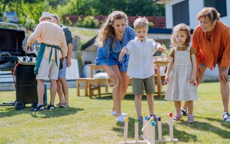 a group of people playing a game of croquet in a backyard.