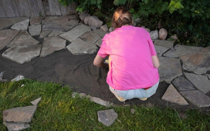 a girl is laying a flagstone stone