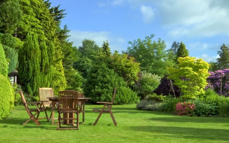 a garden with a wooden table and chairs.