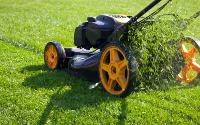 a lawn mower cutting grass on a green field.