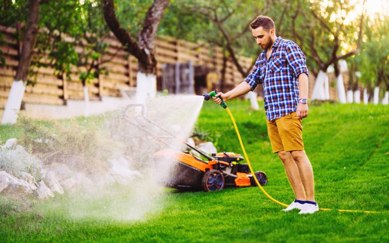 a man spraying his lawn with a lawn mower.