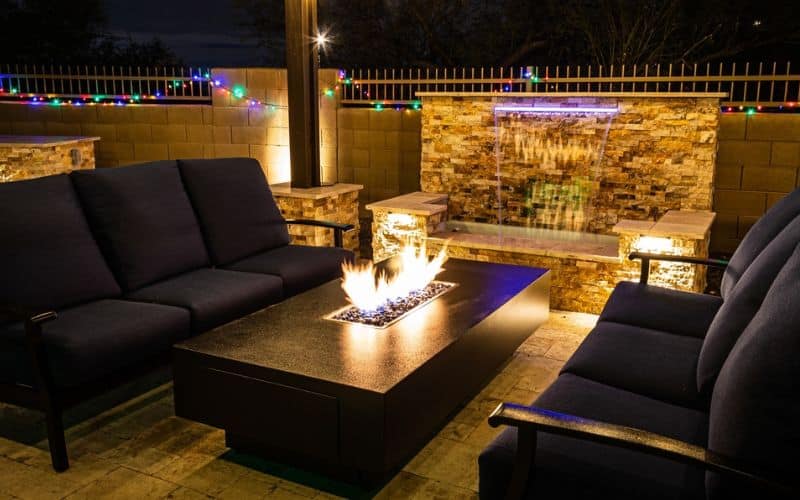 a pergola with couches and a fire pit.