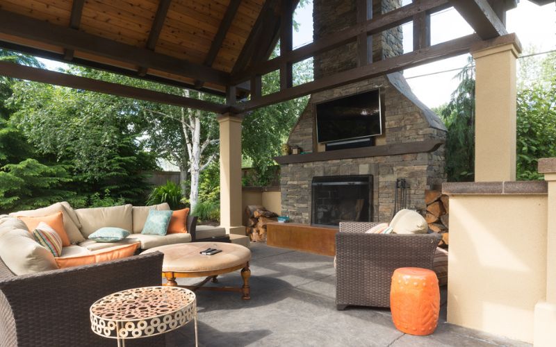 an outdoor living area with a fireplace and wicker furniture.