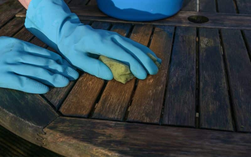 a person in blue gloves cleaning outdoor furniture.