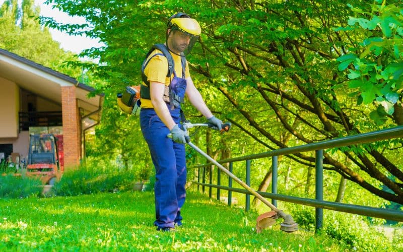 A man using a weed whacker and wearing a protective gear