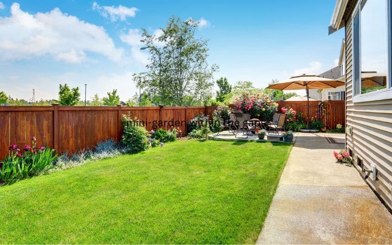 A backyard with green grass and a wooden fence.