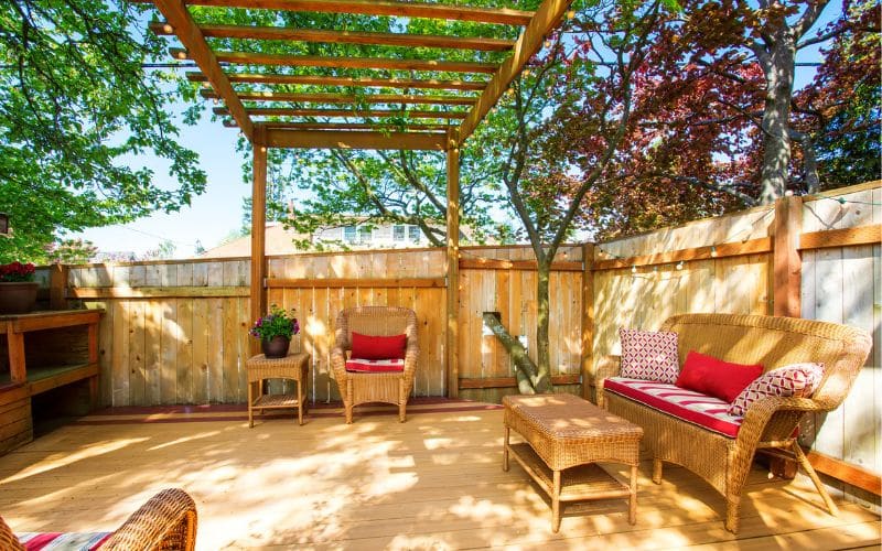 A backyard with wicker furniture and a pergola.