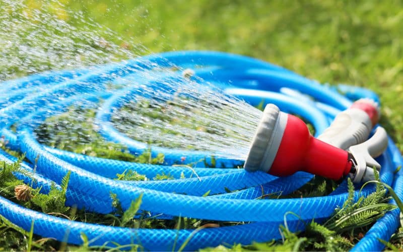 A blue hose with a water hose on the grass.