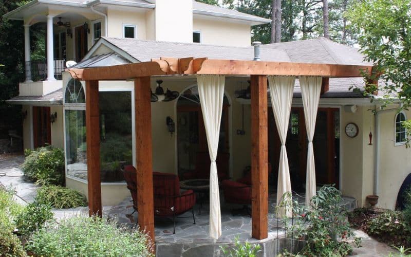 An outdoor patio with a pergola and chairs.