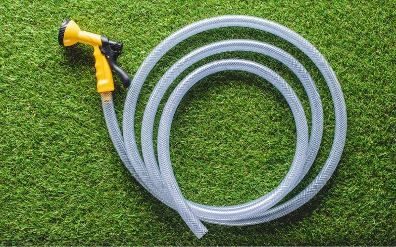 A garden hose with a yellow hose on a green grass.