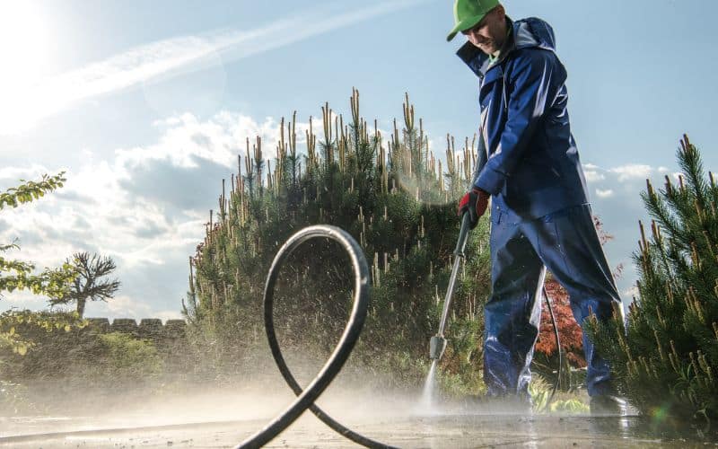 A man spraying a garden with a pressure washer