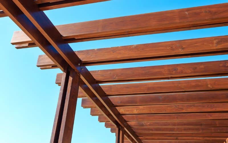 An image of a wooden pergola against a blue sky.