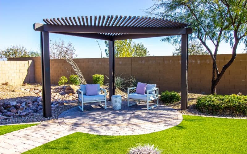 A backyard with artificial grass and a freestanding pergola