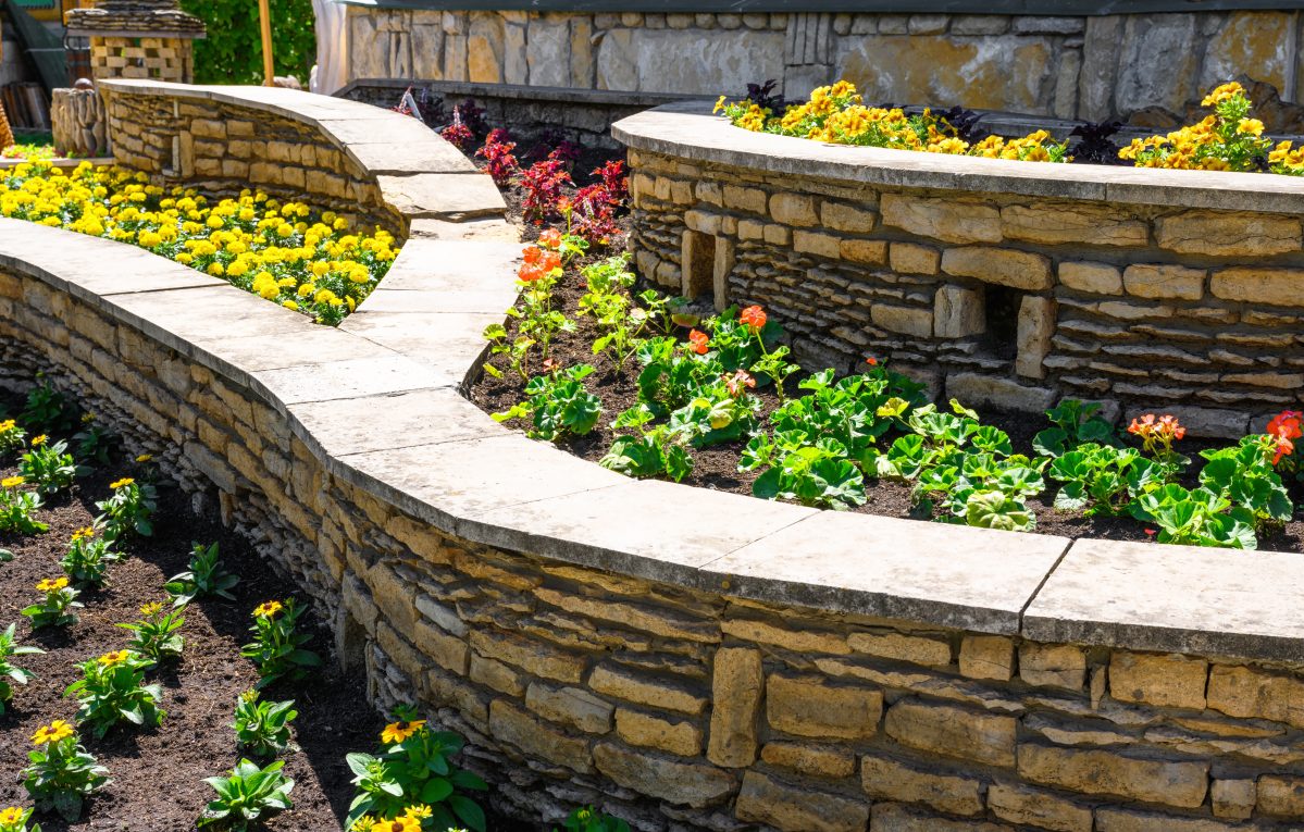 A stone retaining wall with flowers in it.