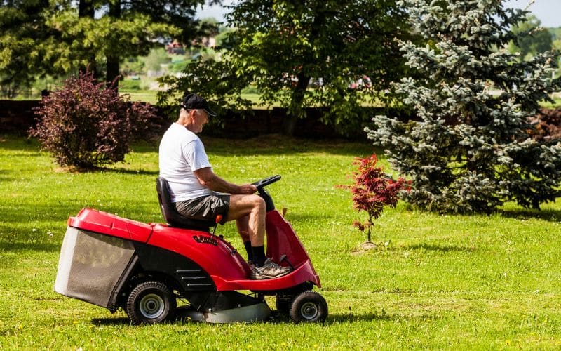 A man riding a lawn mower in a park.