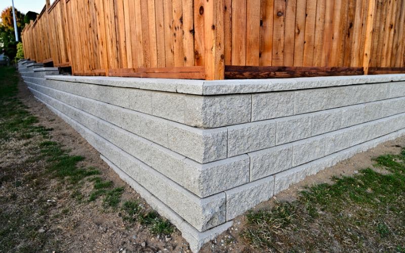 A concrete retaining wall with a wooden fence.
