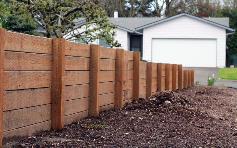 A wooden retaining wall in front of a house.