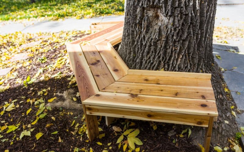 A bench made out of wood next to a tree.