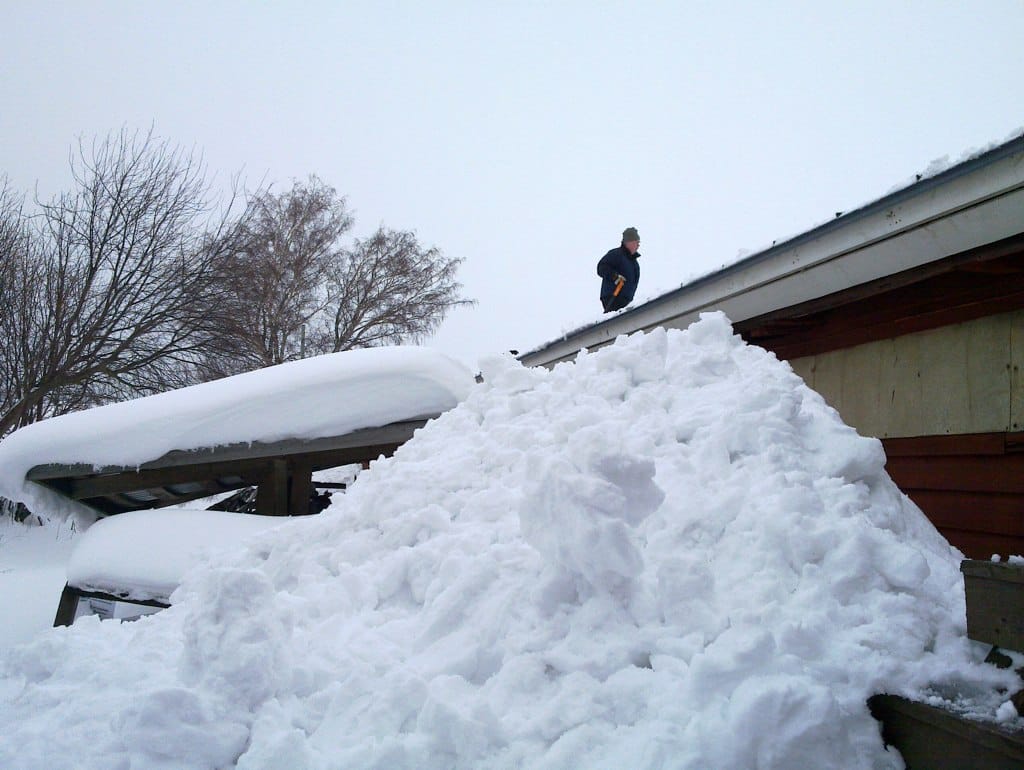 homeowner removing snow from their roof