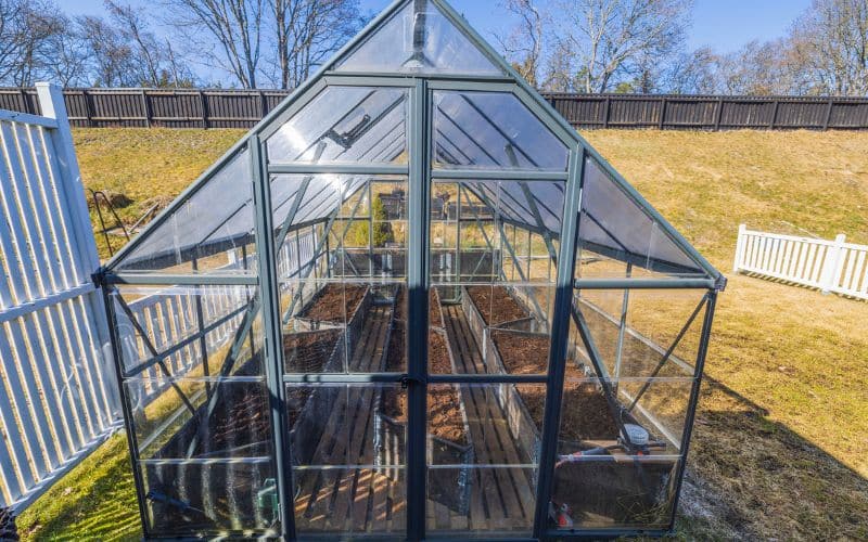 Detailed view of a raised garden bed kit in autumn with cold frames and cloches, showing kale and spinach thriving in cooler temperatures.